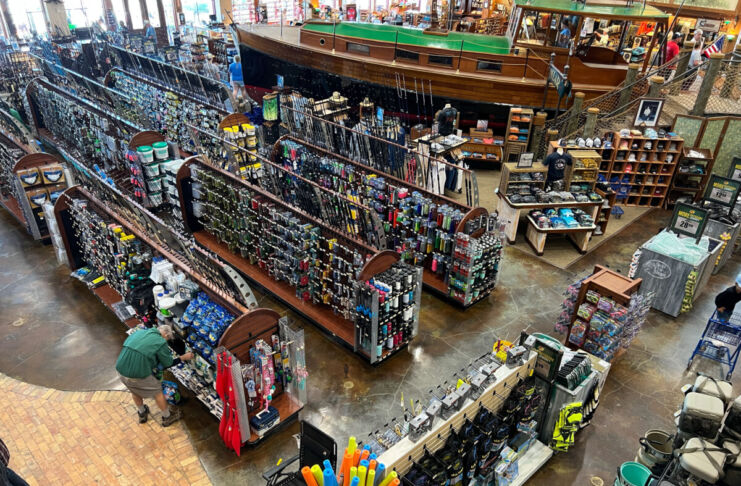 Ein Mann steht zwischen vielen Regalen in einem großen Laden. In dem Sortiment des Geschäfts gibt es Kleidung, Accessoires und verschiedene Souvenirs.