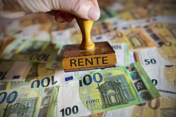 Mehrere ausgebreitete 50- und 100-Euro-Scheine liegen nebeneinander auf einer Fläche. Darüber hält jemand in einer Hand einen Stempel mit der Aufschrift "Rente".