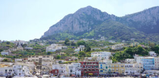 Capri - mitten im Sommer - eine beliebte Urlaubsinsel der deutschen Touristen liegt direkt am Meer. Im Hintergrund liegen hohe Berge und grüne Wälder.