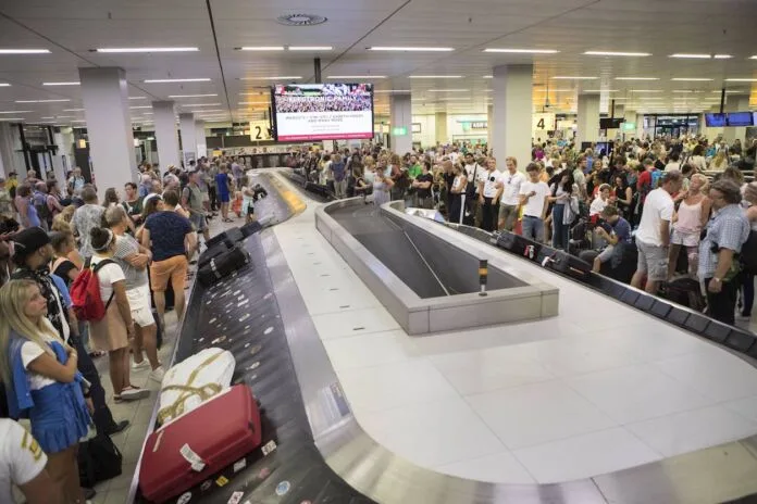flughafen Gepäckband gepäck warten menschen menge fluggäste reise koffer terminal Passagiere Ankunft Nach ihrer Ankunft am Flughafen wartet eine große Menschenmenge am Gepäckband auf ihre Taschen und Koffer. Im Hintergrund hängt ein Bildschirm für Informationen für die reisenden Passagiere. Deutschland setzt nun härtere Einreise-Kontrollen durch.
