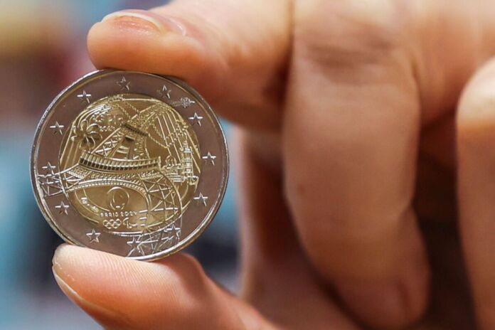 Eine Hand hält zwischen Daumen und Zeigefinger eine seltene 2-Euro-Münze. Das 2-Euro-Stück ist besonders wertvoll und bei Sammlern beliebt.