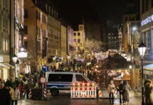 Nach Hamburg: Auch Kult-Weihnachtsmarkt in Rostock gestrichen Die Polizei steht mit einem Fahrzeug auf einem weihnachtlich geschmückten Weihnachtsmarkt. Für den Einsatz auf der Veranstaltung wurden Absperrungen in der Innenstadt aufgestellt.