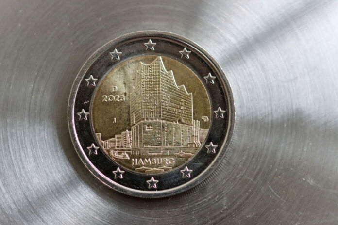 Die Rückseite einer 2-Euro-Münze mit der Aufschrift "Hamburg". Die Münze liegt auf einem silbernen Untergrund. Als Motiv ist die Hamburger Elbphilharmonie aufgedruckt. Das Motiv in der Mitte wird von 12 Euro-Sternen umgeben.