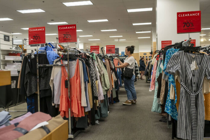 Auf einem Kleiderständer hängt Kleidung für Damen und Herren. Die Mode steht zum Verkauf, einige Kleidungsstücke sind reduziert. Die Kunden können bei der Shoppingtour sparen.