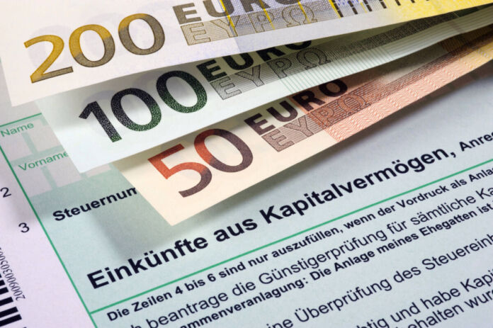 Auf einem Formular zur Erklärung über die Einkünfte aus Kapitalvermögen liegen ein 50-, ein 100- und ein 200-Euro-Schein. Sie verdecken den Teil, auf dem der Name und die Steuernummer des Bürgers eingetragen werden müssen.