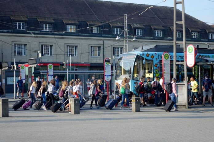 Fahrgäste stehen am Bahnhof vor der S-Bahn. Sie warten auf die Ankunft des Zuges. Mit dabei sind auch Besucher und Touristen, die Karlsruhe besuchen und sich die Innenstadt und die Sehenswürdigkeiten anschauen.