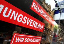 Das Schaufenster einer Filiale. Auf dem Fenster sind mehrere Aufkleber in roter Farbe sichtbar. Auf den Aufklebern steht "Räumungsverkauf" und "Wir schliessen". Das Geschäft ist geschlossen.