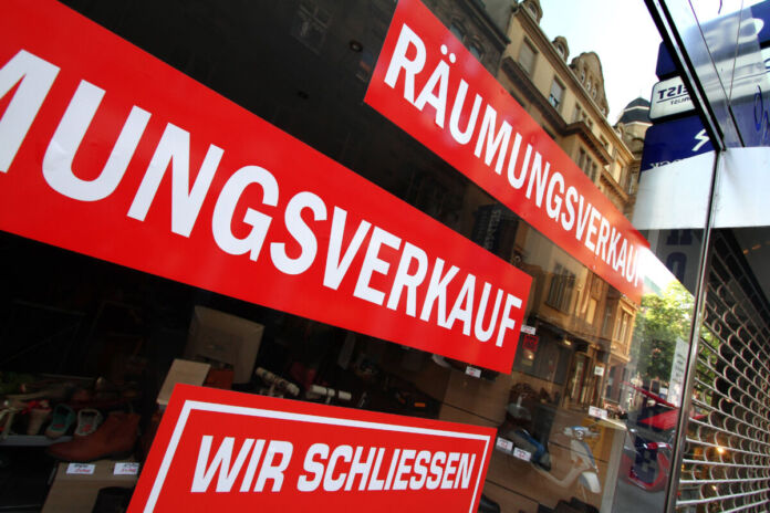 Das Schaufenster einer Filiale. Auf dem Fenster sind mehrere Aufkleber in roter Farbe sichtbar. Auf den Aufklebern steht "Räumungsverkauf" und "Wir schliessen". Das Geschäft ist geschlossen.