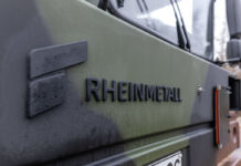 Das Logo von Rheinmetall auf einem Fahrzeug. Vermutlich handelt es sich dabei um einen Lastwagen. Dieser ist in Tarnfarben des Militärs gehalten.