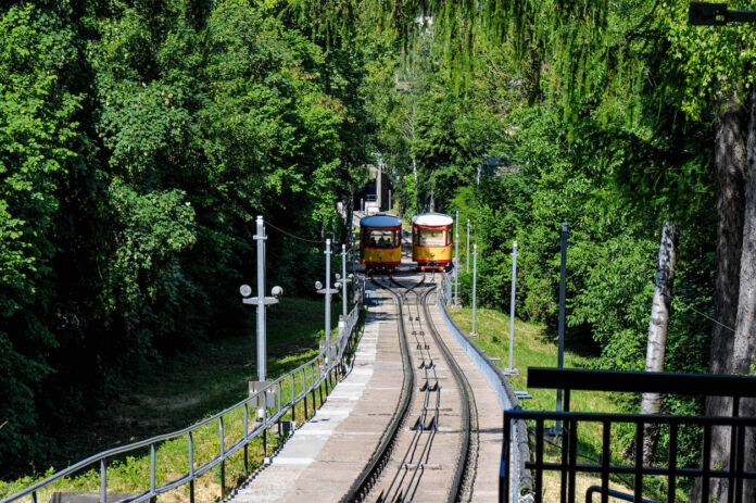 In einer malerischen Landschaftsszene schlängelt sich Deutschlands älteste noch betriebene Standseilbahn auf den Gleisen bergauf, um Fahrgäste zu transportieren. Die Turmbergbahn soll für immense Kosten erneuert werden.