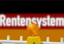 Vor der Deutschland-Fagge steht in weißen Buchstaben das Wort Rentensystem. Am vorderen Rand des Bildes befindet sich eine Absperrung, die üblicherweise für Baustellen verwendet wird.